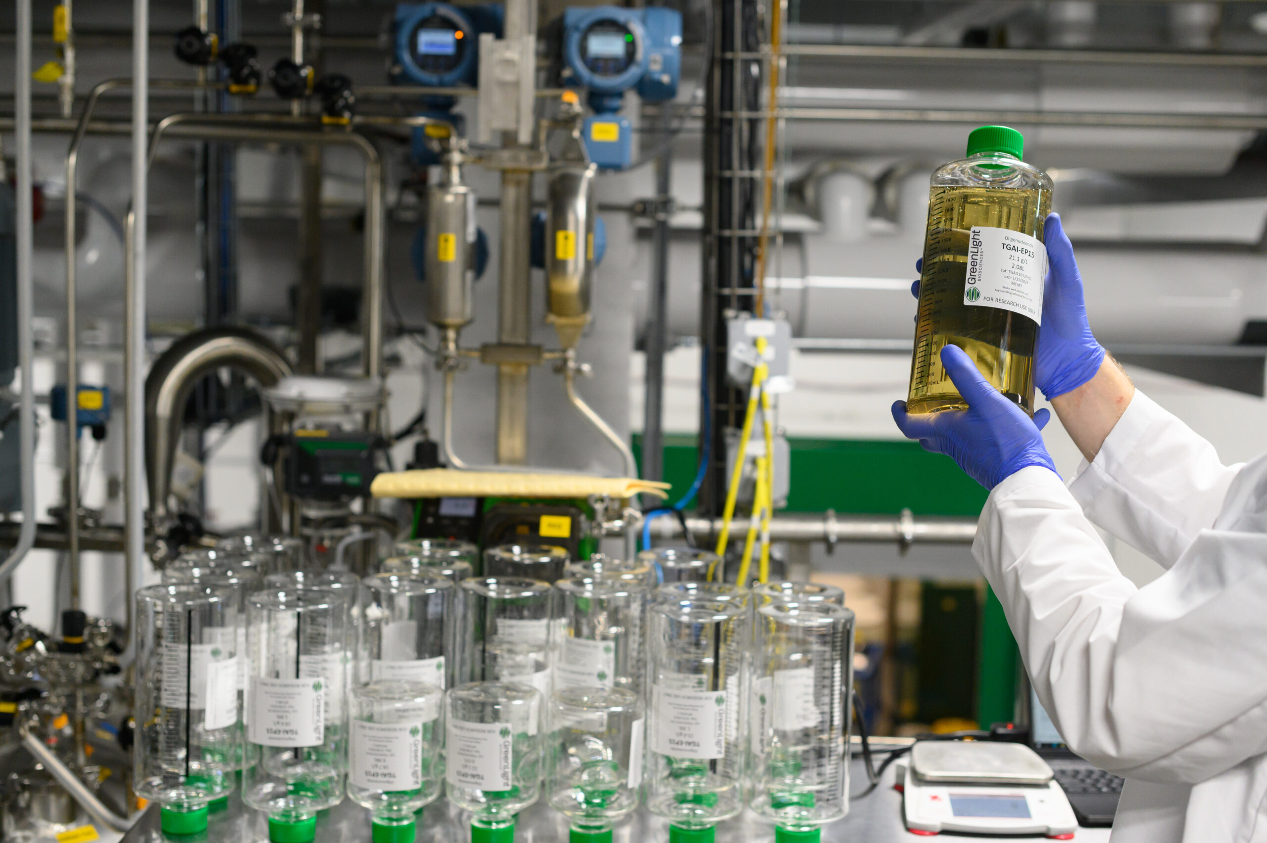 a scientist holds up a glass flask in GreenLight's Rochester facility